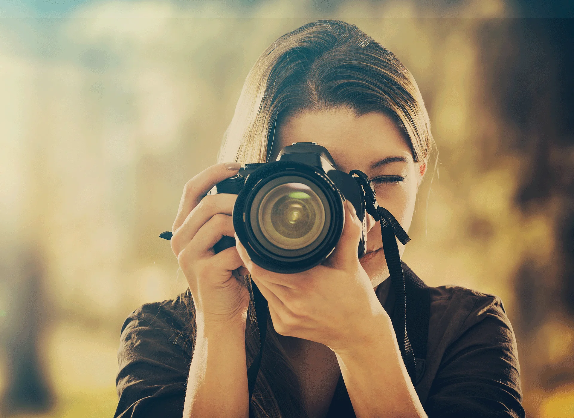 Imagen en primer plano de una fotógrafa y su cámara mientras hace una foto.